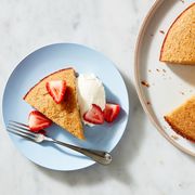 slice of almond cake on a blue plate with strawberries and whipped cream