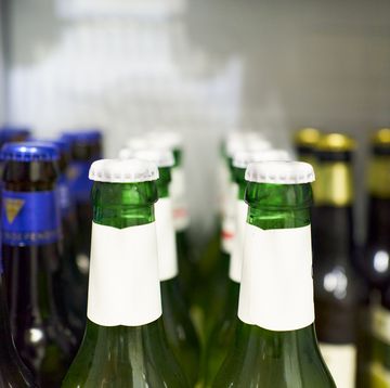 close up of beer bottles with white cap and beers with blue and gold details in the background inside the refrigerator