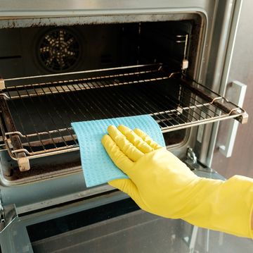 man with rag and rubber gloves cleaning kitchen stove